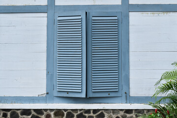 Grey wall with ancient blue windows. 