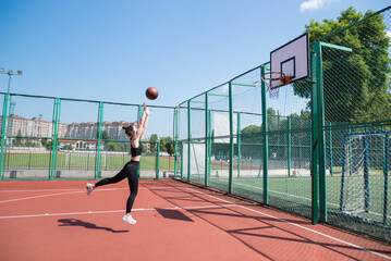Athletic female basketball player throwing a ball up to the net.