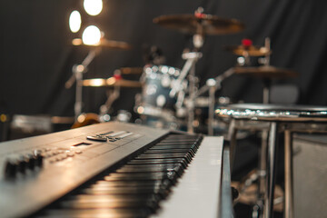 Teclado sintetizador color negro con el fondo de una batería e iluminado al final