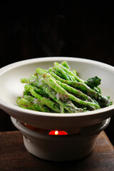 Fried green vegetables, a special dish made by a Chinese chef, in a white bowl, indoor shot, dark background