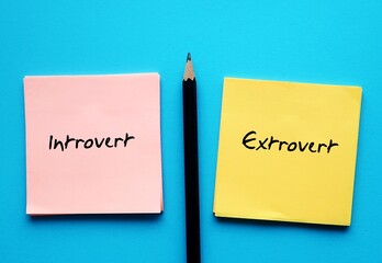 notepad on blue copy space background with handwritten text - INTROVERT EXTROVERT, different traits...