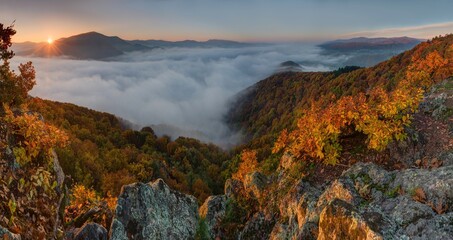 Autumn landscape with rocks, colorful leaves on the trees, inversion, fog and rising sun. Awesome Autumn landscape. 