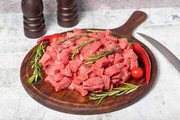 Raw beef meat chopped in cubes. Diced beef or lamb on a wooden serving board