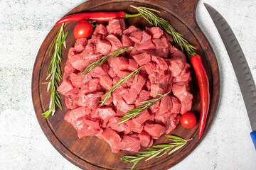 Raw beef meat chopped in cubes. Diced beef or lamb on a wooden serving board