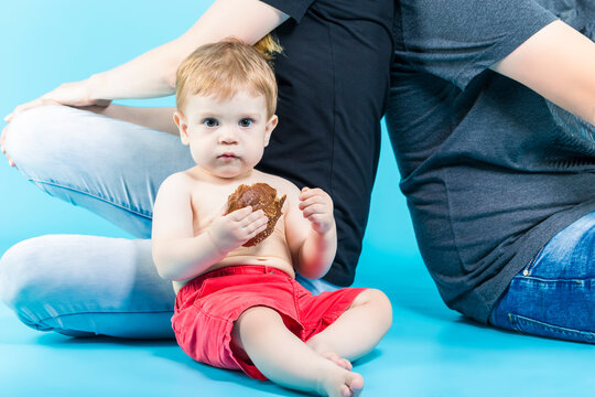 Closeup of Caucasian Kid With Bun Sitting Together With Parents Against Blue Background.