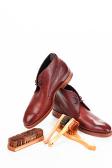 Pair of Tanned Derby Boots Made of Calf Leather with Leather Sole Placed In Line With Shoe Cleaning Brushes On One Another On Pure White