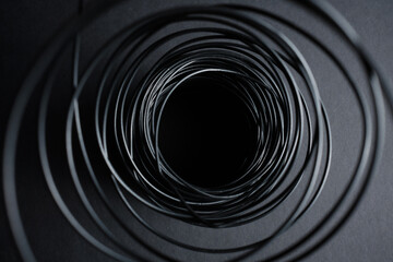 dark background on gray paper background black wire twisted into a spiral