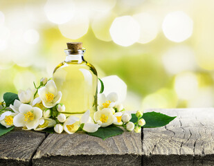 White jasmine flowers with green leaves and transparent glass bottle with Essential oil