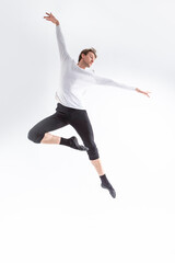 Fototapeta na wymiar Professional Caucasian Handsome Young Athlete Man Posing in Flying Ballet Pose with Lifted Hands in White Shirt On White.