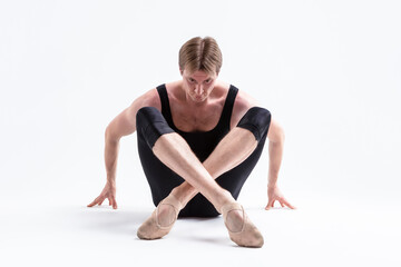 Fototapeta na wymiar Closeup Image of Male Ballerino Dancer Sitting While Practising Stretching Exercices In Black Sportive Tights in Studio