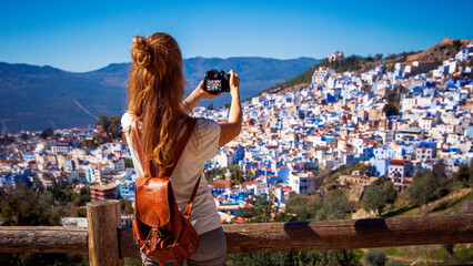 Woman tourist taking picture of blue city- Chefchaouen in Morocco - obrazy, fototapety, plakaty