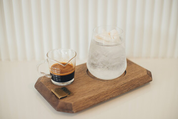 Close up and selective focus glass of coffee and coconut juice on wooden plate at cafe.