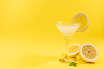 Fresh summer fruits water or lemonade with lemon on yellow background. Close up.