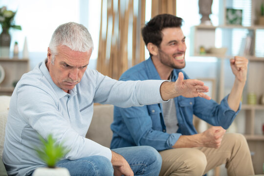 happy adult son and senior father playing video games