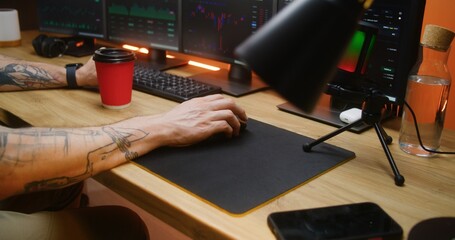 Male trader uses computer mouse, types on keyboard, analyzes real-time stocks, exchange market charts on multi-monitor PC. Man works remotely in investment or cryptocurrency at home office. Close up.
