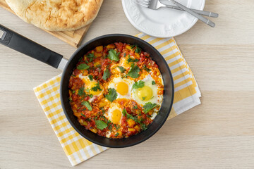 Keto meal, low carb. Traditional shakshuka with eggs, tomato, and parsley in a iron pan. Dish of eggs poached in a sauce of tomatoes, chili peppers, onions