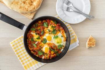 Keto meal, low carb. Traditional shakshuka with eggs, tomato, and parsley in a iron pan. Dish of eggs poached in a sauce of tomatoes, chili peppers, onions