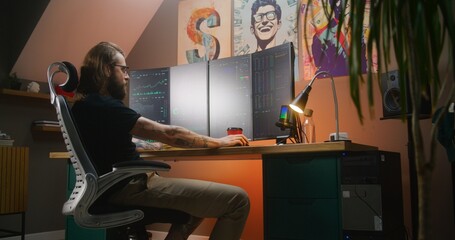 Male financial analyst watches real-time stocks, exchange market charts on multi-monitor computer, eats french fries. Man works in investment in cozy room at home office. Cryptocurrency trading.