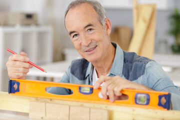 portrait of senior carpenter using spirit level