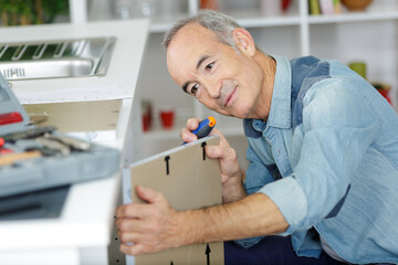 mature male fitting door onto kitchen cupboard