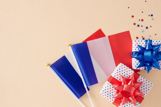 Bastille Day gifting concept. Top view photo of french flags, patriotic gift boxes, stars confetti on pastel beige background with space for ads or text