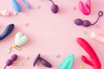 Adult erotic toys concept. Top view arrangement of vibrators, anal plugs, vaginal balls, colorful hearts on pastel pink background with empty space for text or advert © Goncharuk film
