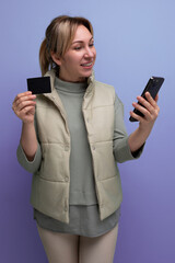 young 30s woman uses smartphone to work with money card