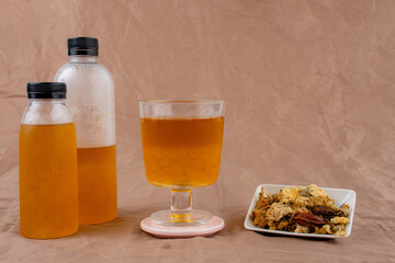 Cold water of chrysanthemum flowers and dried chrysanthemum flowers on brown background.