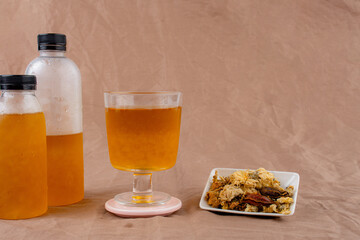 Cold water of chrysanthemum flowers and dried chrysanthemum flowers on brown background.