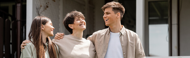 happy parents day, cheerful young adult son and teenage daughter hugging middle aged mother on backyard of summer house, family celebration, bonding, moments to remember, modern parenting, banner