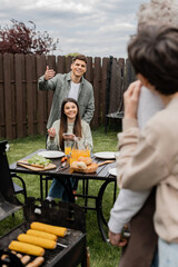 parents day celebration, happy siblings looking at father and mother on blurred background, inviting to table, gesturing, family bbq, grill party, preparing food on grill bbq, modern parenting