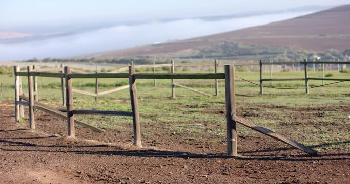 Wooden fence on agricultural field at countryside on sunny day, slow motion