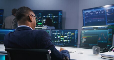 Software programmer sits in front of computer with blockchain network and data server in monitoring...