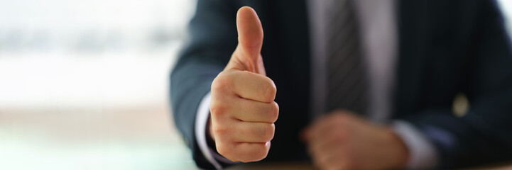Businessman showing thumb up at work in office closeup. successful business people concept