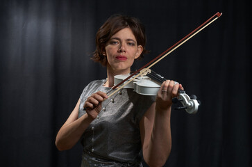 Fototapeta na wymiar Half-length portrait of a woman playing the violin on a black background