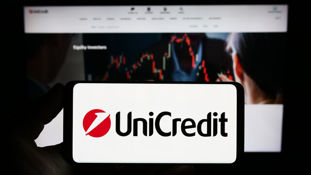 Stuttgart, Germany - 06-17-2023: Person holding smartphone with logo of Italian financial company UniCredit S.p.A. on screen in front of website. Focus on phone display.