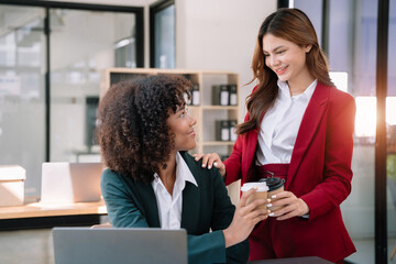 female colleague of half Asian descent holds a cup of coffee and smiles happily.