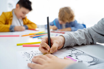 Children drawing paint with colorful pencils coloring book in educational class at school. Art...