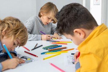 Children drawing paint with colorful pencils coloring book in educational class at school. Art...