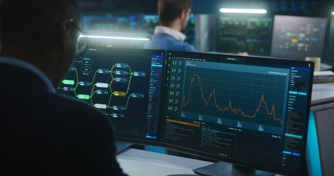 Multiracial team of IT software engineers work in monitoring office. Data server, blockchain network and live analysis charts displayed on computers and big digital screens. Concept of cyber security.