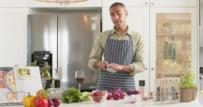Biracial male cooking vlogger in apron talking and filming in kitchen