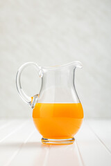 A pitcher of fruit juice. Orange  juice on white table.