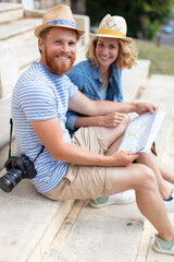 tourist couple sitting on steps looking at city map © auremar