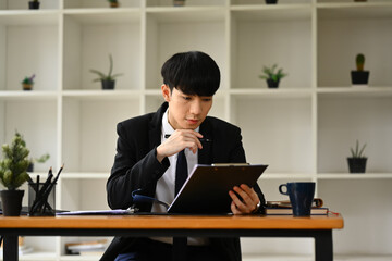 Focused young businessman analyzing financial data and planning marketing strategy at workplace