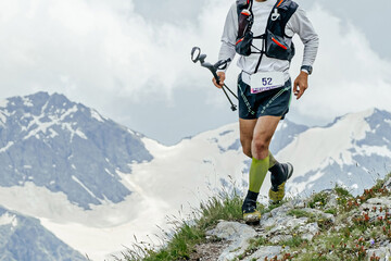 athlete runner running mountain trail skyrunning race on edge of cliff, trekking poles in hand © sports photos