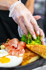 woman chef hand cooking fried eggs with ham, salad and hummus