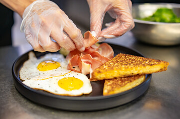 woman chef hand cooking fried eggs with ham, salad and hummus