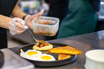 woman chef hand cooking fried eggs with ham, salad and hummus