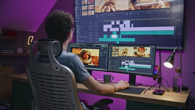 Young editor works at home office, edits sound tracks for video or movie about space mission. Film footage and software interface with tools on PC and big digital screen. Concept of post production.