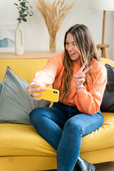 Long haired woman sitting at home taking selfie.